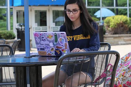 Nicole Andino working on her laptop in front of the Mountainlair.