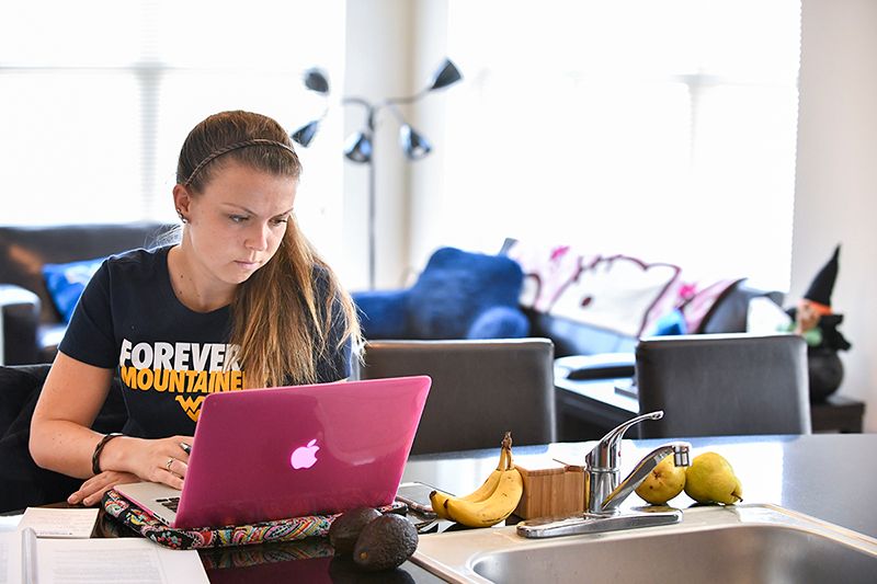 Female WVU student working on her laptop from home.